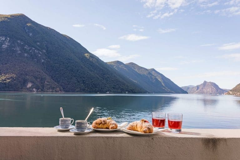 Espresso, juice and cornetti on a ledge by a lake